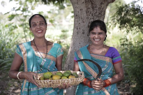 Women holding basket of mangoes